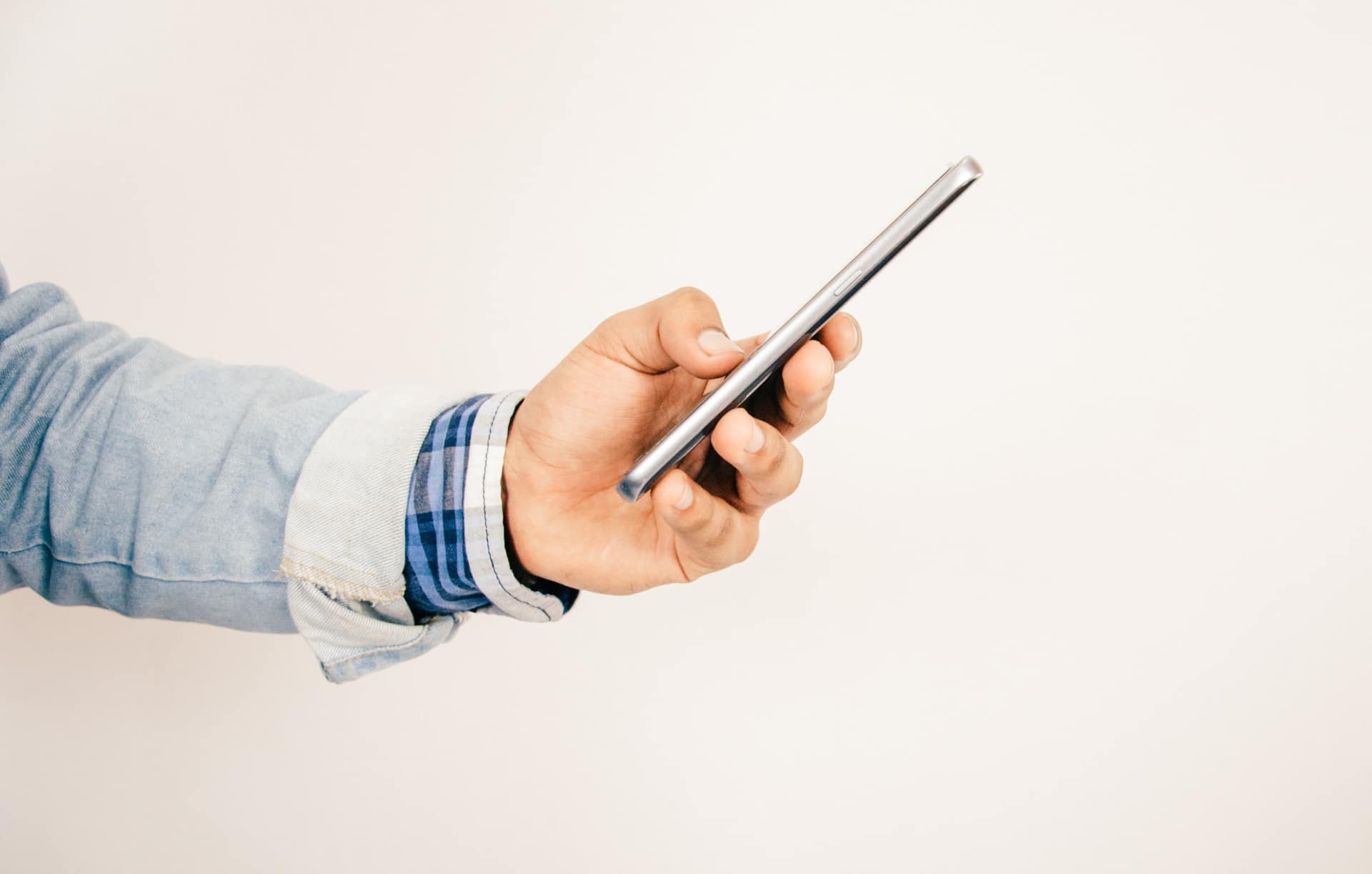 Há muitas marcas de celulares desconhecidas no Brasil, como a não identificável do smartphone que está sendo seguro por um homem na imagem