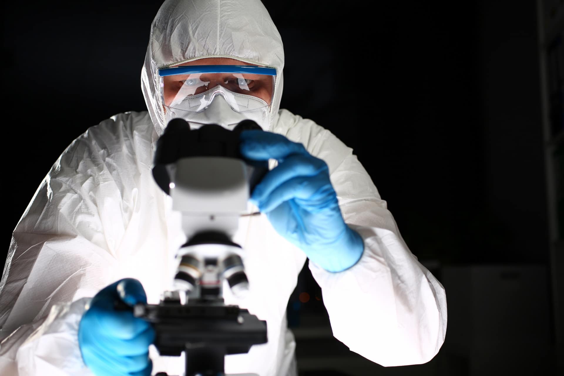 Imagem mostra homem mexendo em microscópio. Chip quase invisível foi projetado para monitorar processos virais de seres vivos