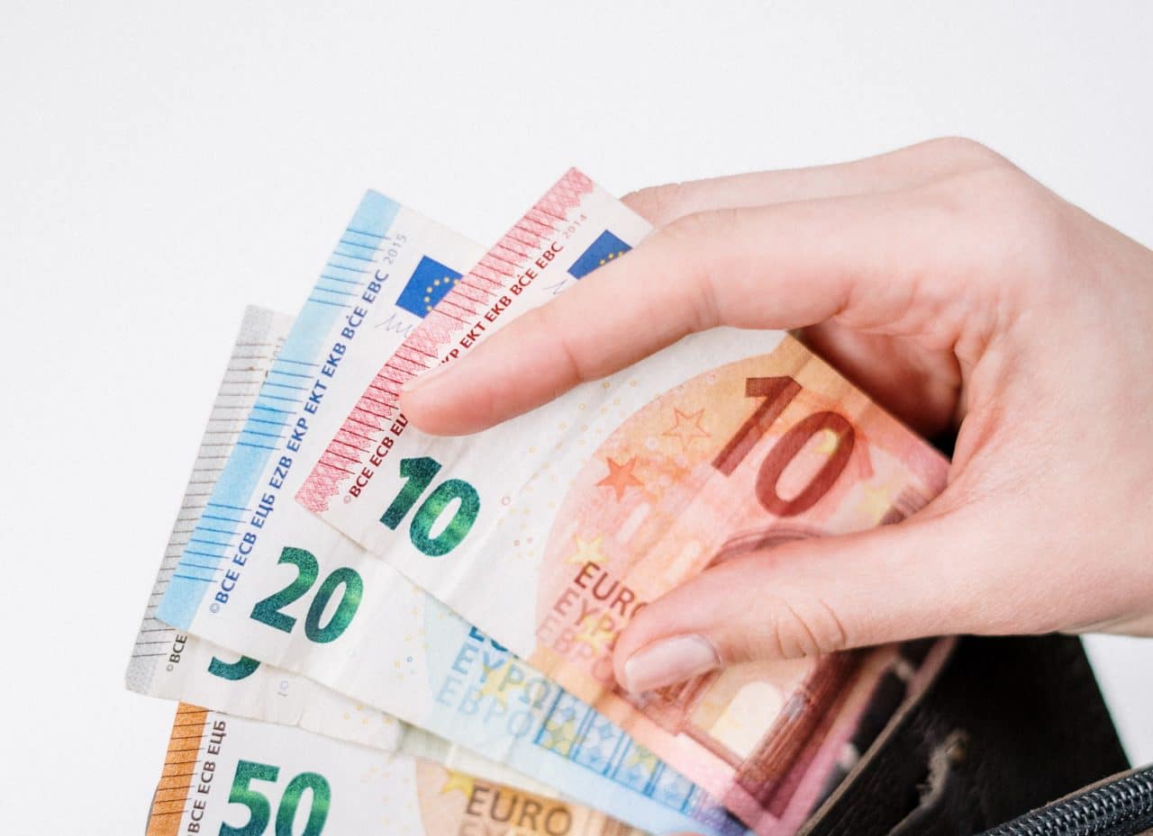 Imagem mostra pessoa abrindo carteira e pegando notas de euros, simbolizando pesada multa que o Google terá de pagar na Itália por supostas irregularidades com o Android Auto