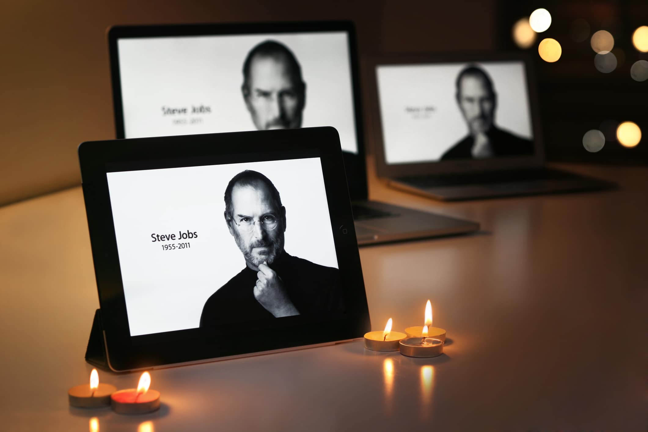 Várias fotos de Steve Jobs sendo exibidas em tablets e notebooks