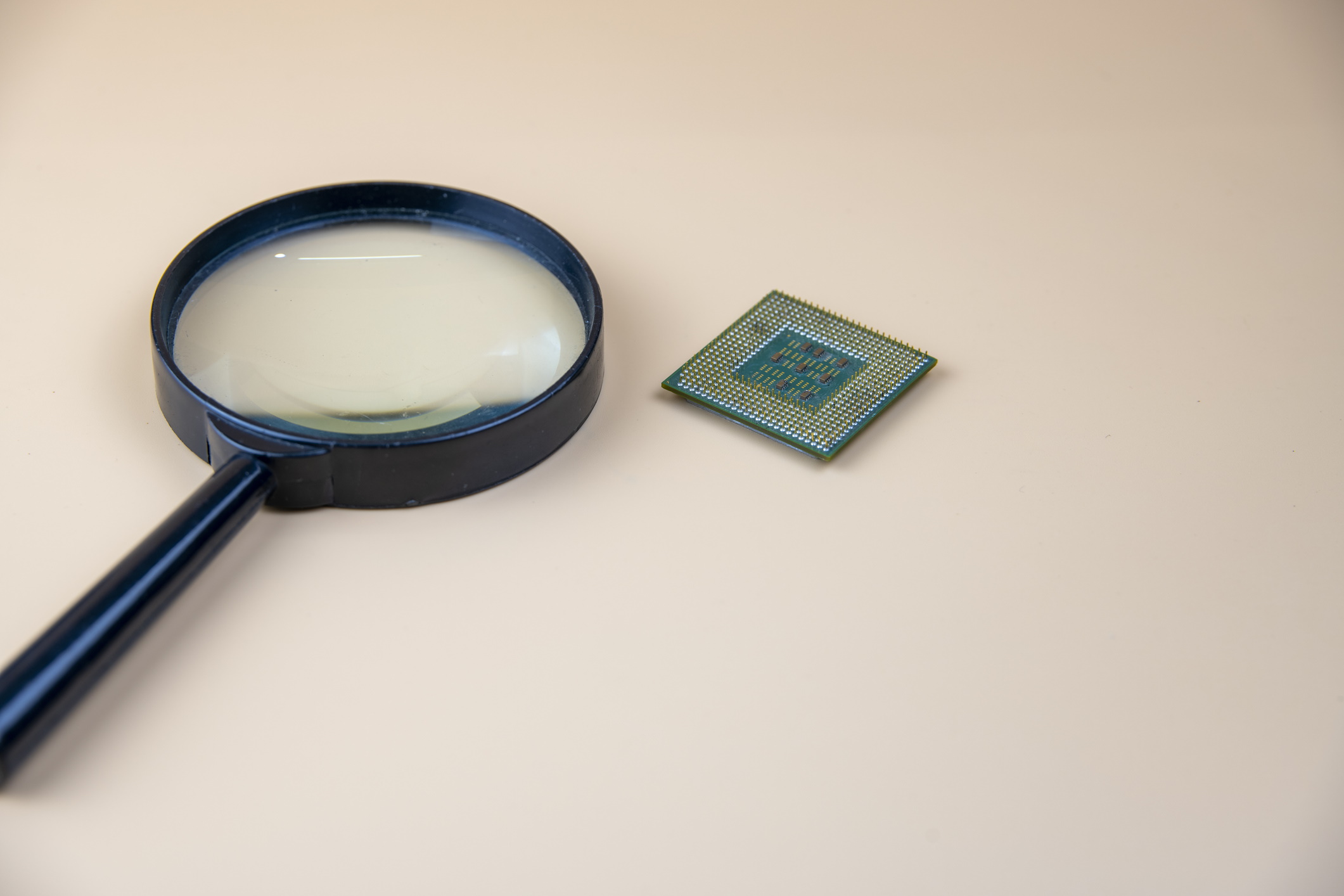 Imagem mostra lupa ao lado de um chipset. TSMC já começou a produzir os processadores do iPhone 13 para a Apple