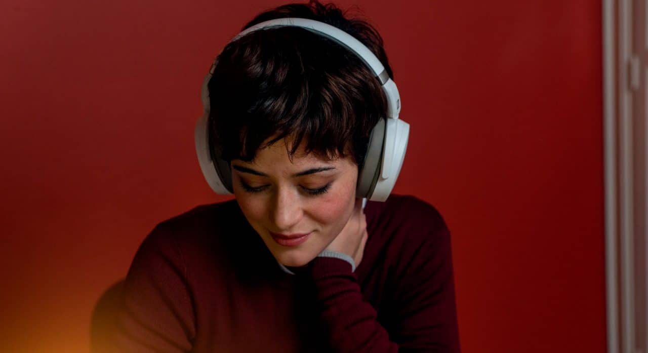 Mulher ouvindo fone da Sennheiser, que foi vendida para a Sonova
