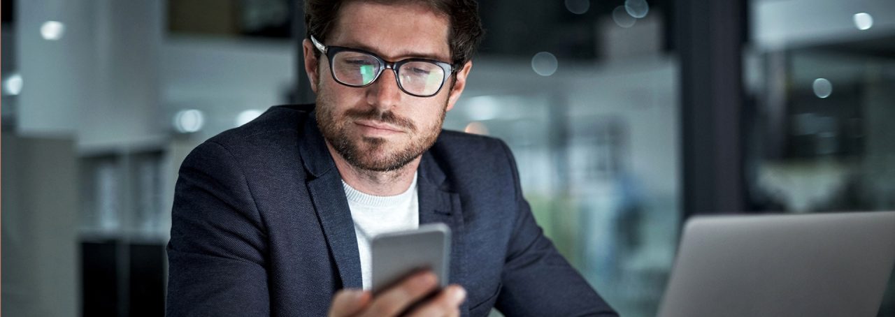 Homem de óculos olhando para a mensagem no celular
