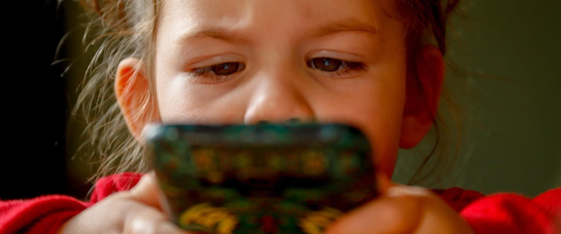 criança vendo vídeo no YouTube pelo celular para ilustrar a verificação idade