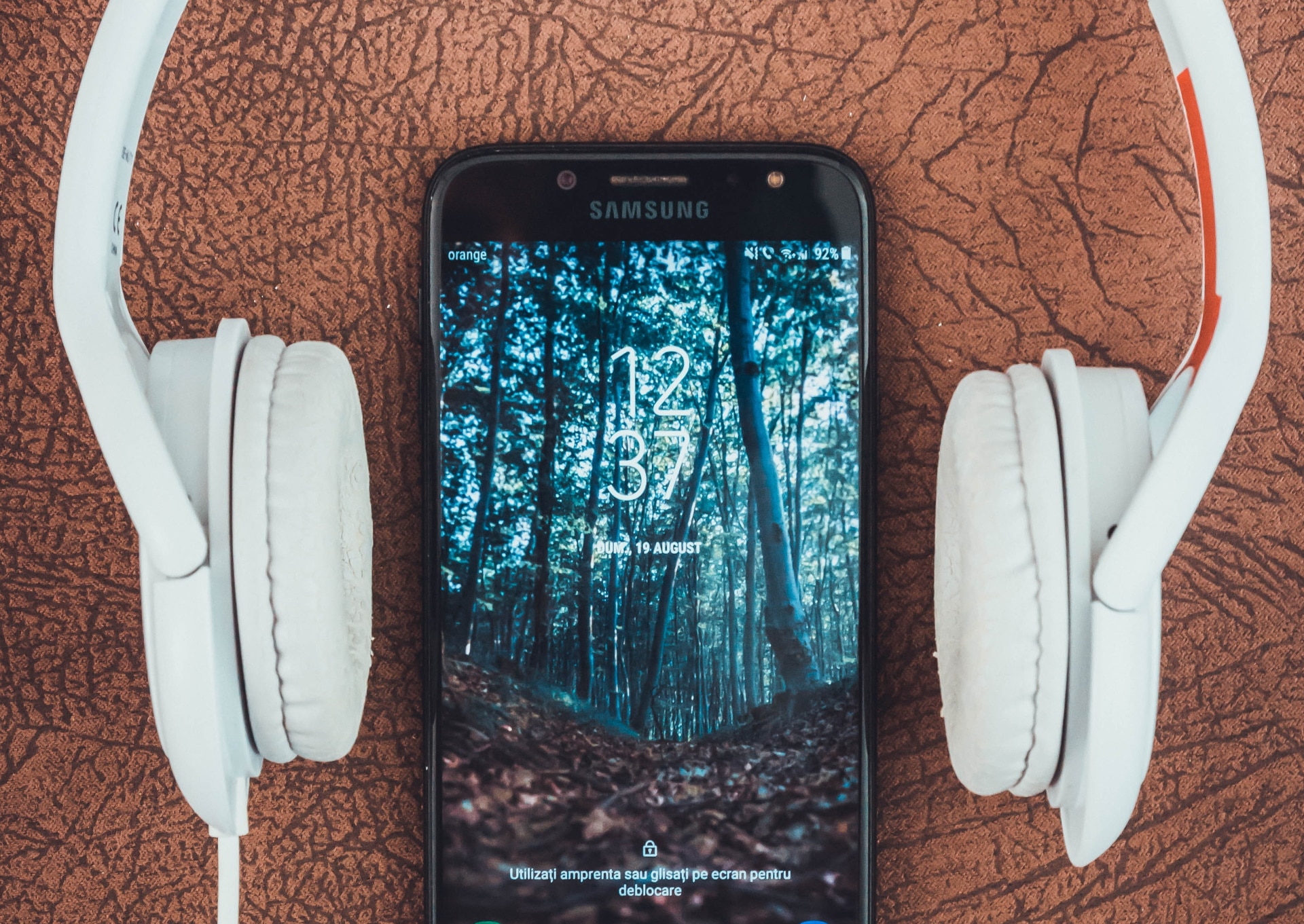 Imagem mostra um smartphone com um fone de ouvido em volta, para ilustrar patente da Xiaomi, que pretende permitir ao usuário carregar o celular pelo som