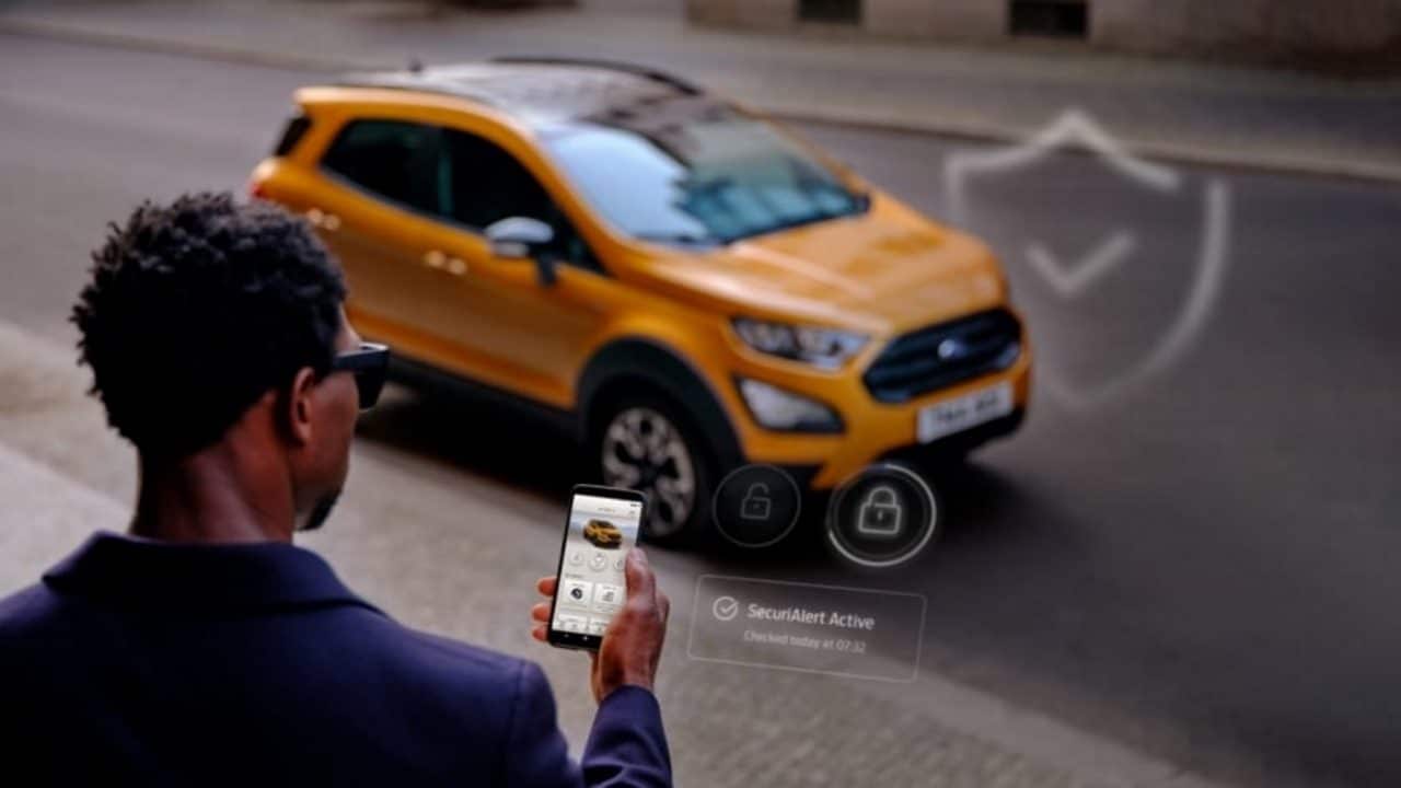 Imagem mostra pessoa segurando celular e carro da Ford ao fundo, para ilustrar app que enviará alerta se houver tentativa de roubo