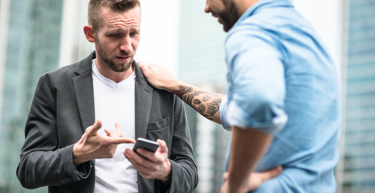 duas pessoas falando com celular na mão