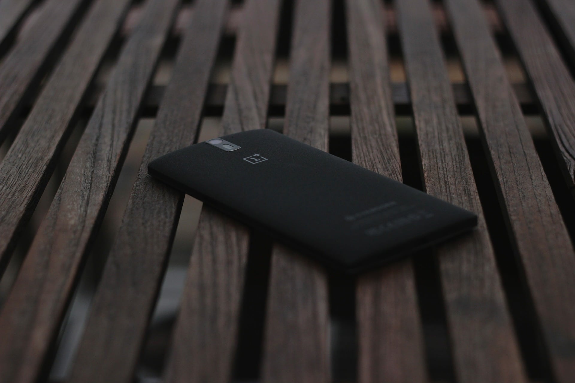 Celular OnePlus preto em uma superfície de tábuas de madeira