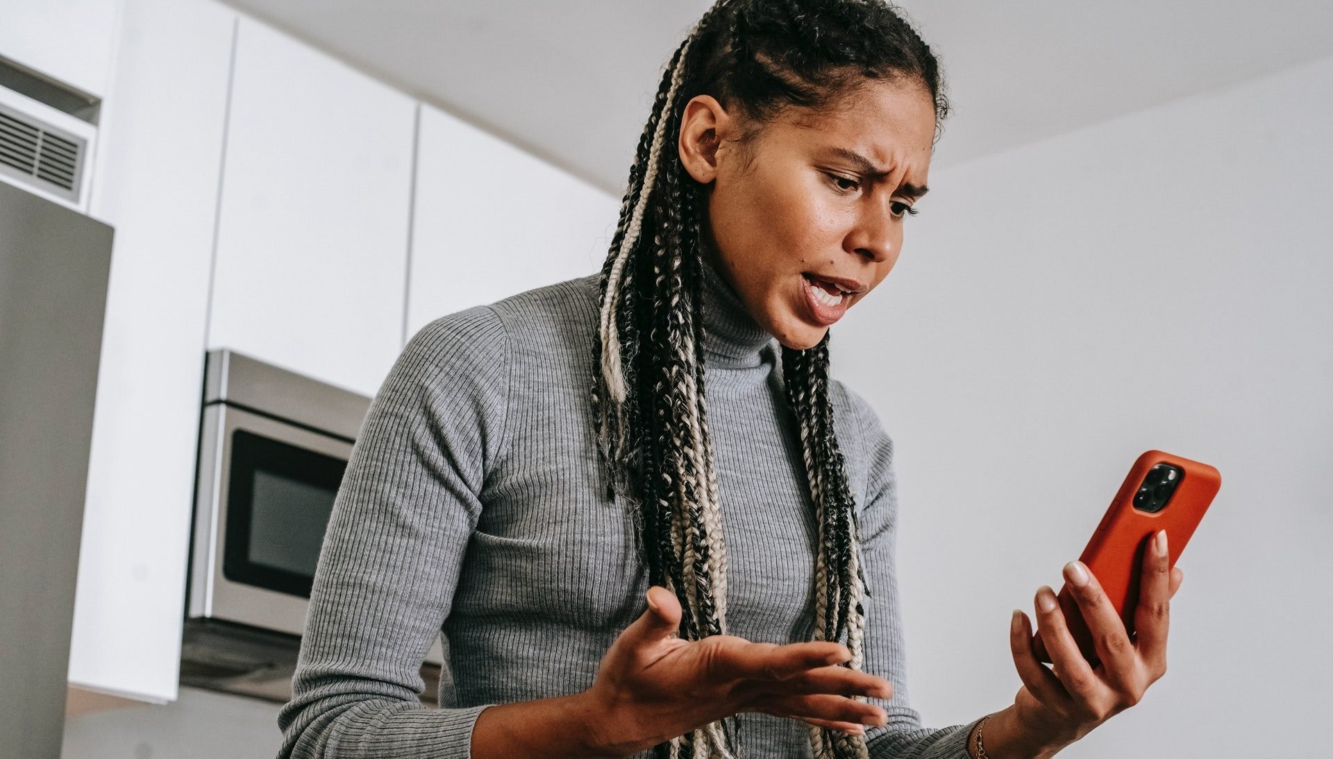 Imagem mostra uma mulher olhando com um semblante de raiva para o celular