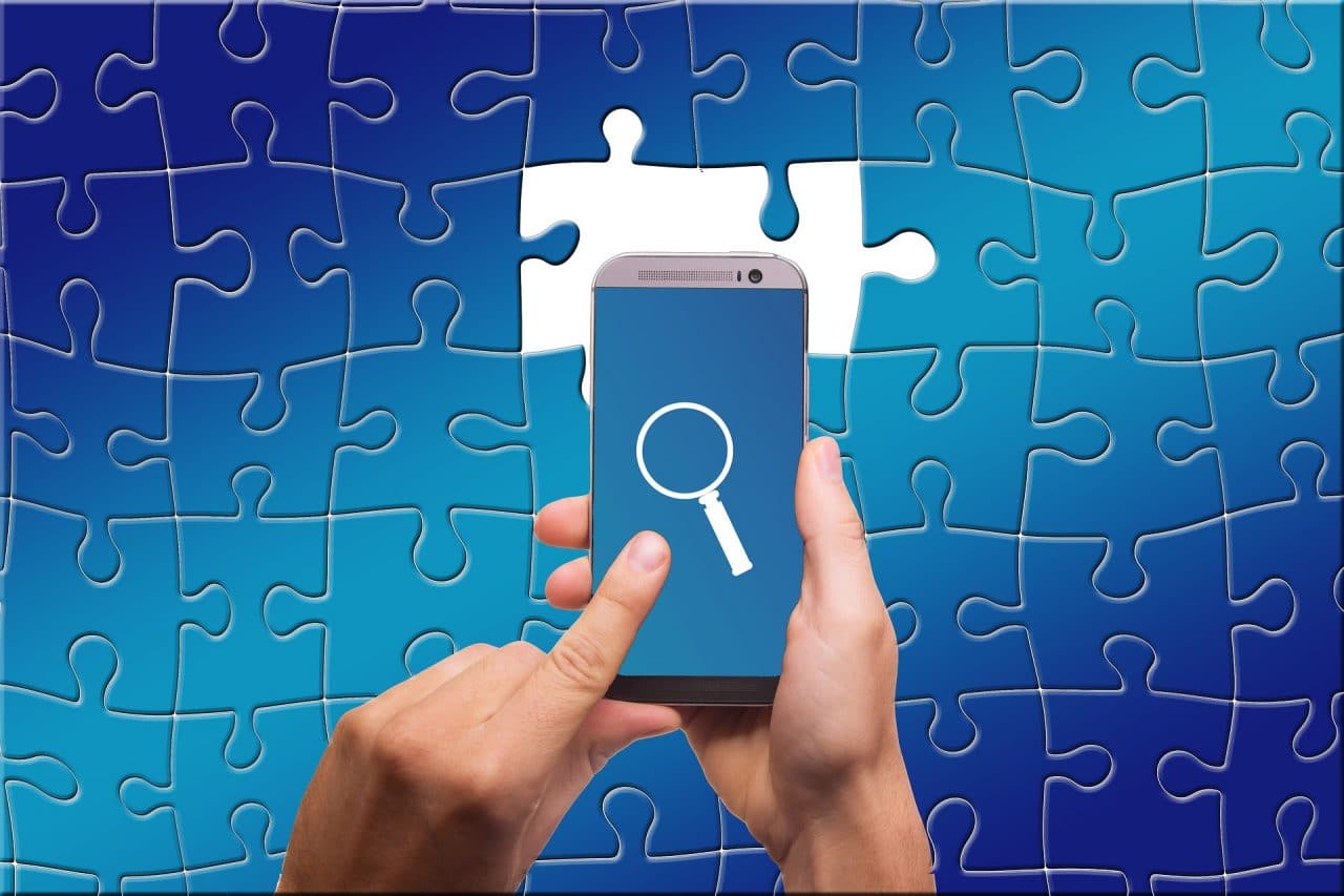 Imagem mostra pessoa tocando em uma lupa na tela do celular e um quebra cabeças ao fundo, como simbolismo para o navegador UC Browser, que rastreia os dados do usuário
