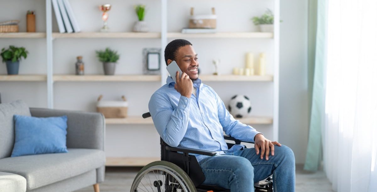 Foto de homem em cadeira de rodas utilizando celular