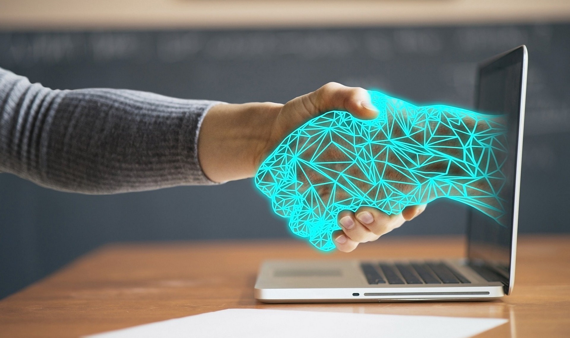 Imagem mostra pessoa apertando mão de uma mão cibernética que sai da tela do computador. Anatel revelou que o Brasil é o terceiro do ranking de segurança cibernética nas Américas