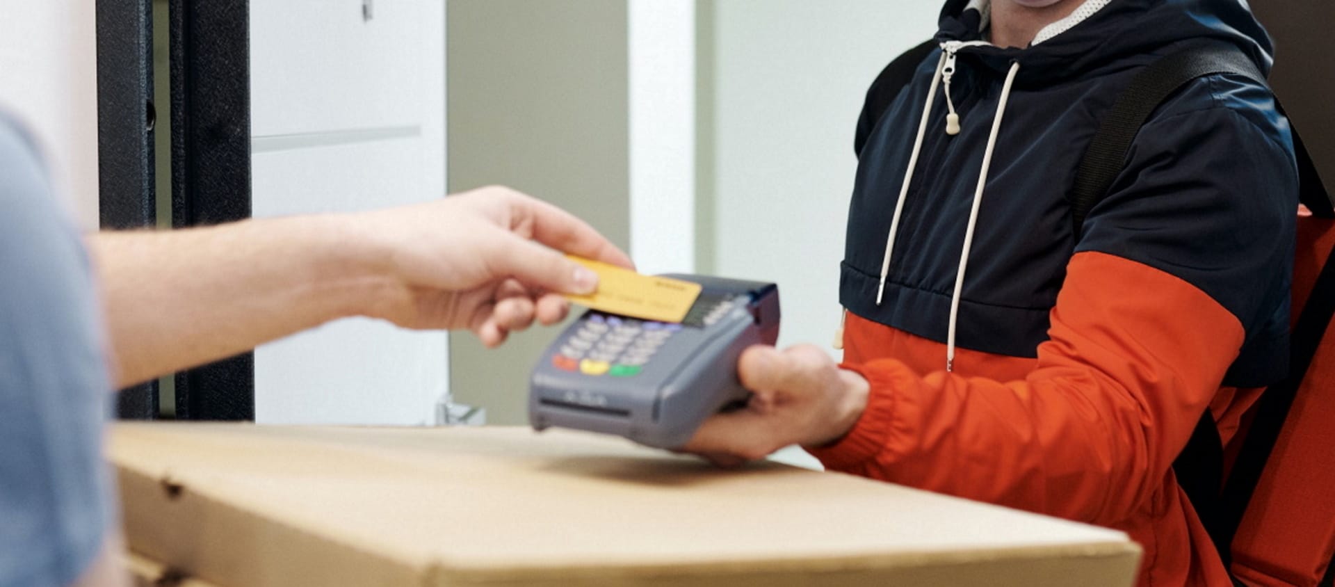 Imagem mostra pessoa realizando pagamento via cartão a entregador de delivery, algo que o Procon-SP quer proibir