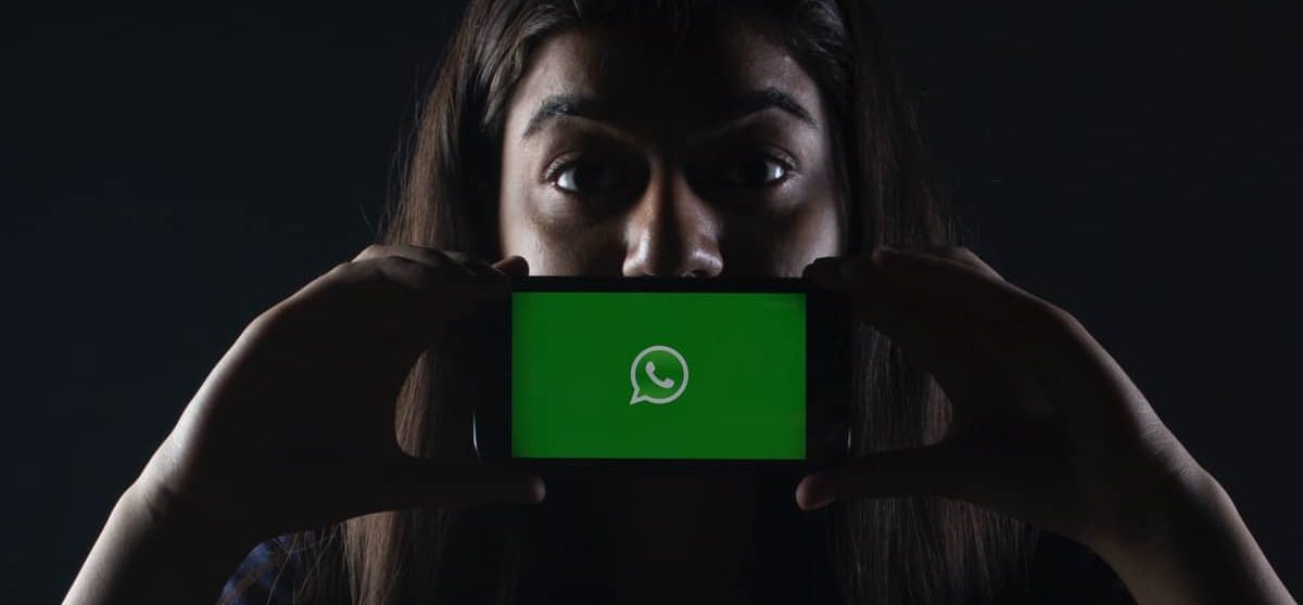 Mulher segurando celular com a tela do WhatsApp