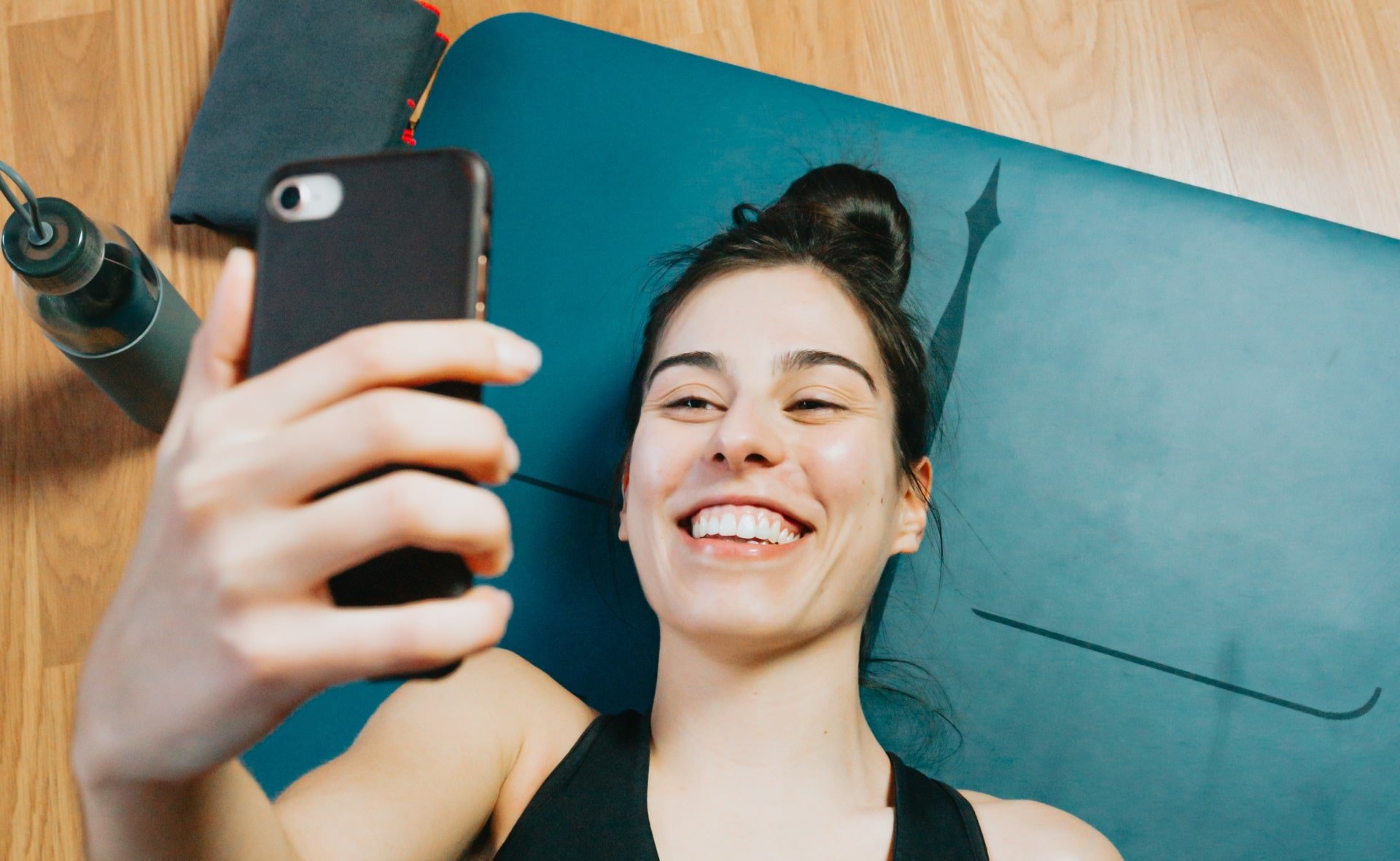 Imagem mostra mulher sorrindo com o celular em mãos. Pesquisa da Anatel vai medir a satisfação dos clientes com serviços telecom
