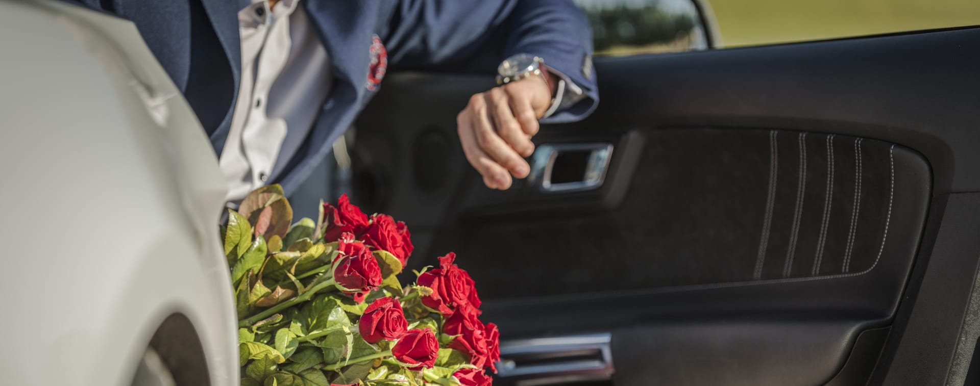 Imagem mostra pessoa sentada no carro, com a porta aberta, flores na mão e olhando no relógio, simbolizando que o Google removerá da Play Store apps que indiquem serviços de sugar daddy (ou mommy)