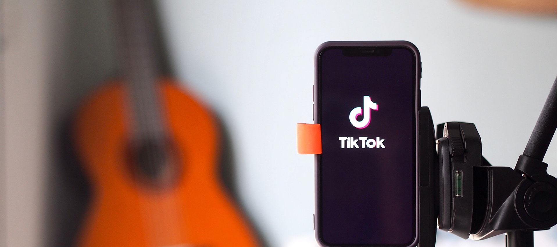 Aplicativo do TikTok aberto com um violão no fundo