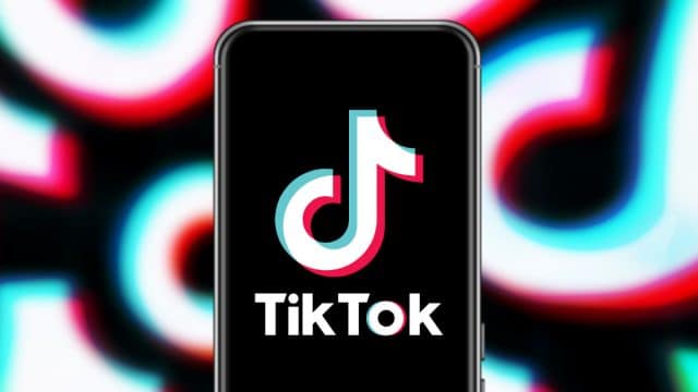 Foto com um celular usando o TikTok e o logo da empresa replicado como padrão ao fundo