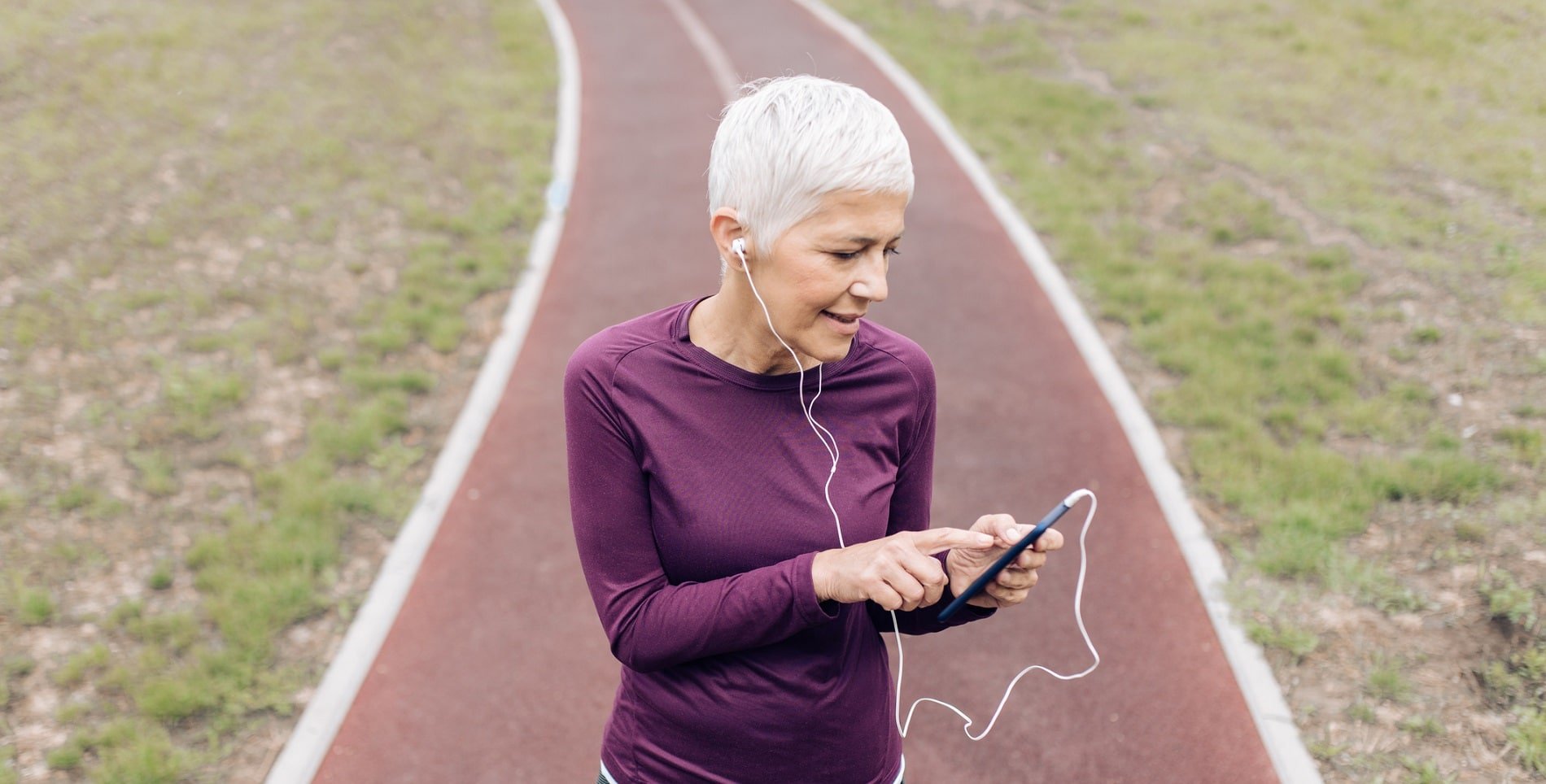 Mulher idosa se prepara para treino físico com smartphone