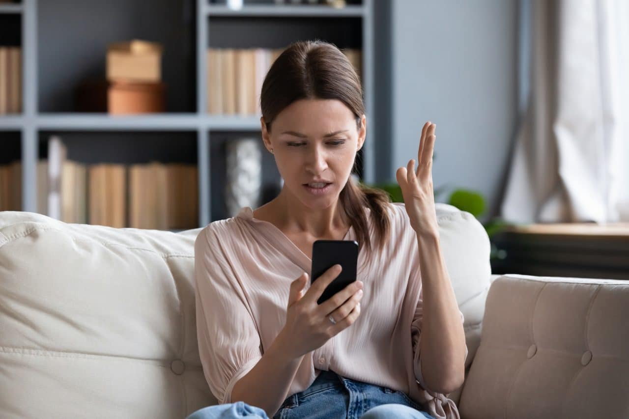 Imagem mostra uma mulher confusa e brava com seu celular