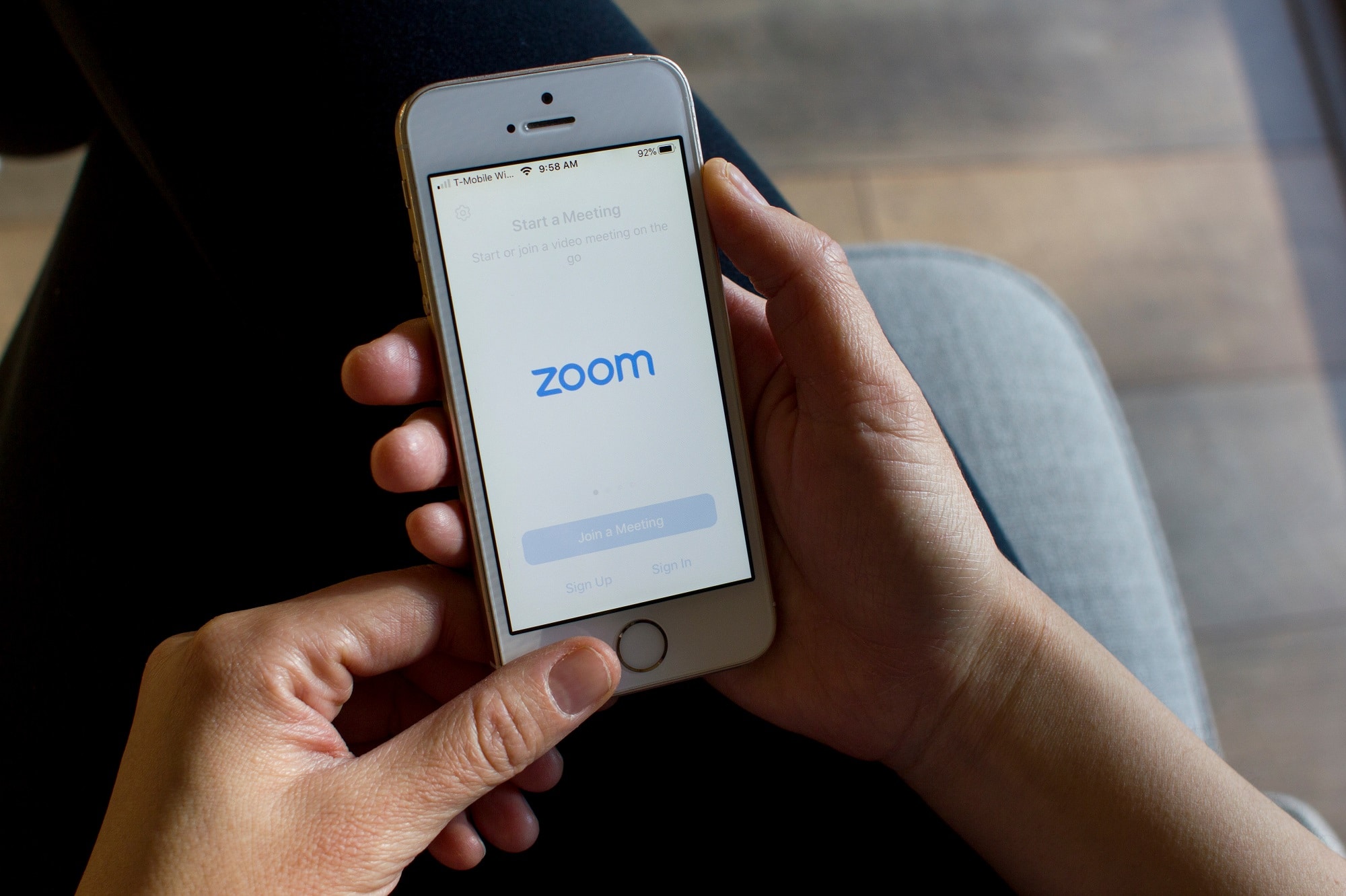 Mulher abrindo a versão mobile do Zoom, empresa processada por compartilhamento indevido de dados sem autorização